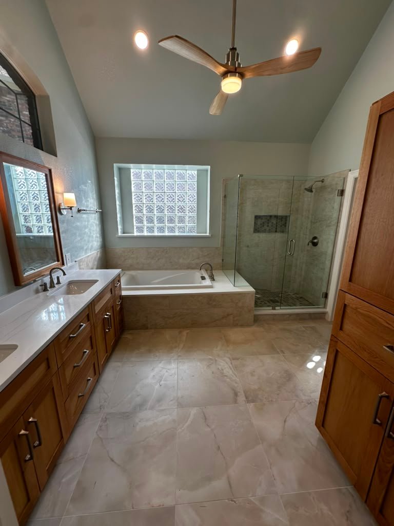 Relocated soaking tub set in a tiled deck beside a walk-in glass shower in Plano TX